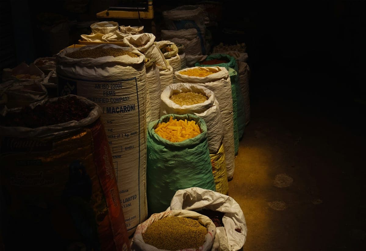 Open sacks of spices lined up at a market stall in low evening light