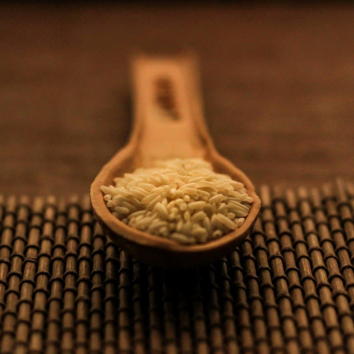 A carved wooden scoop holding pale cumin seeds