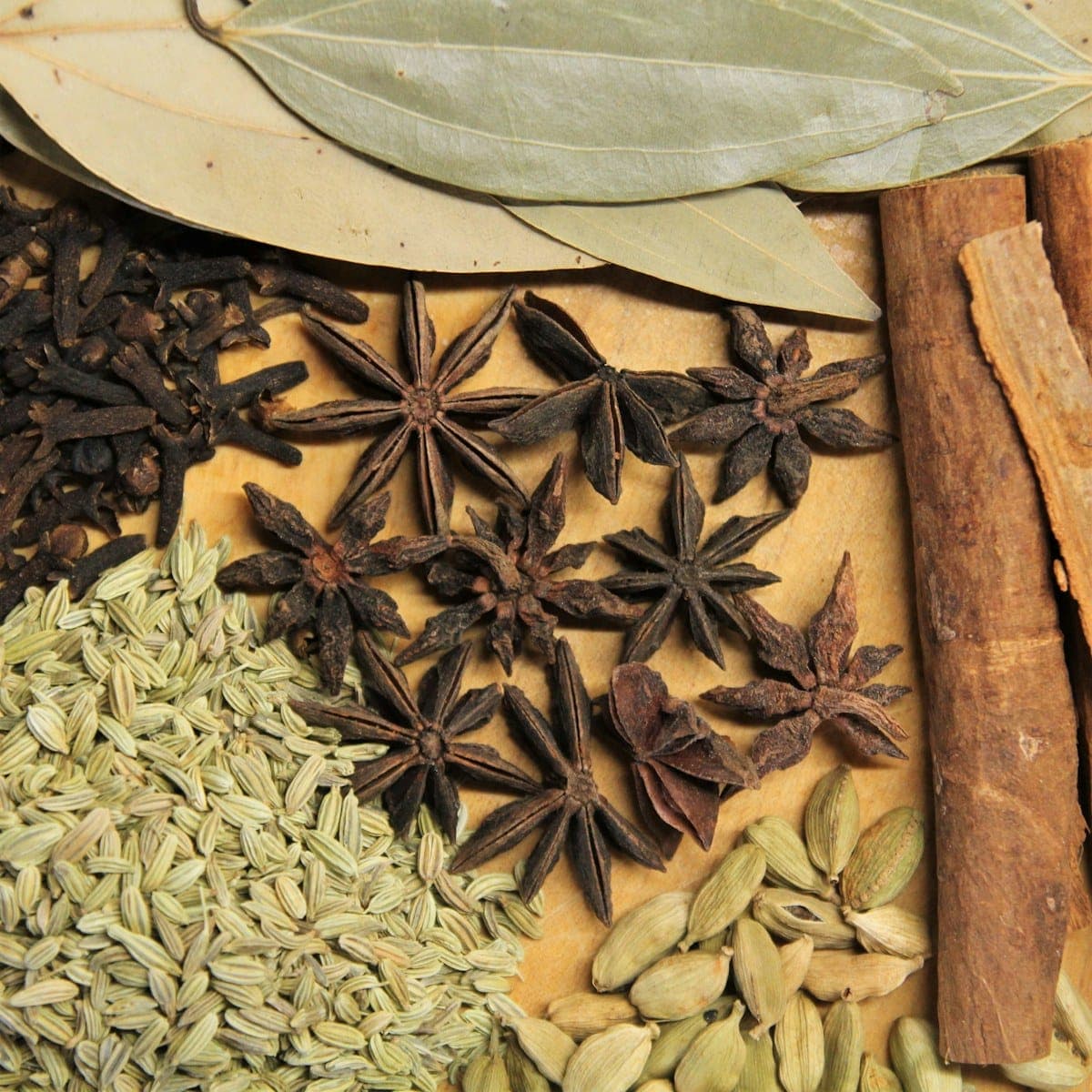 Whole star anise pods scattered among cardamom and bay leaves