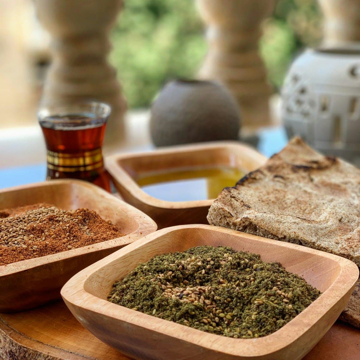 Wooden bowls of green za'atar blend on a sunlit table